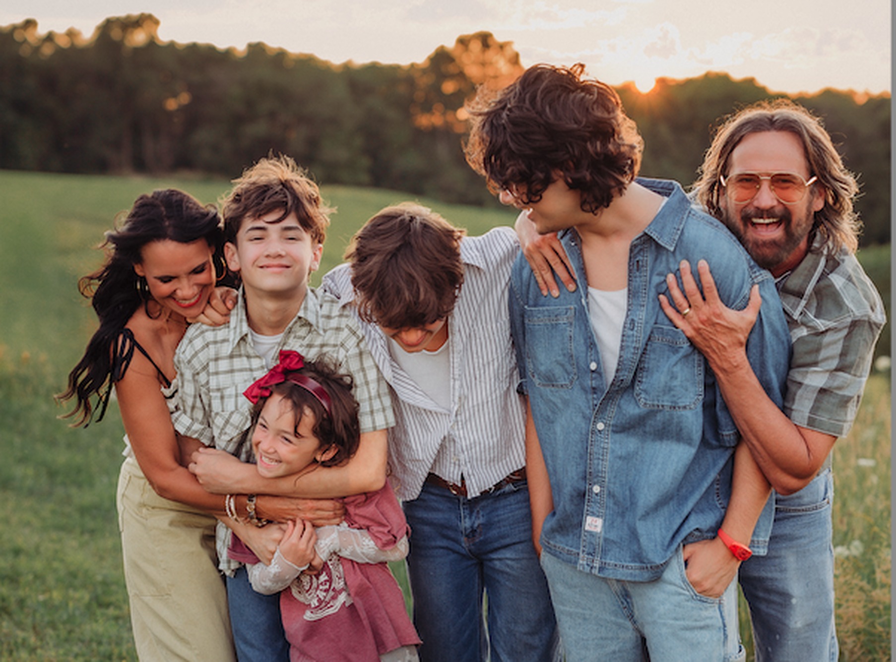 The Waller family laughing together in a green field at golden hour